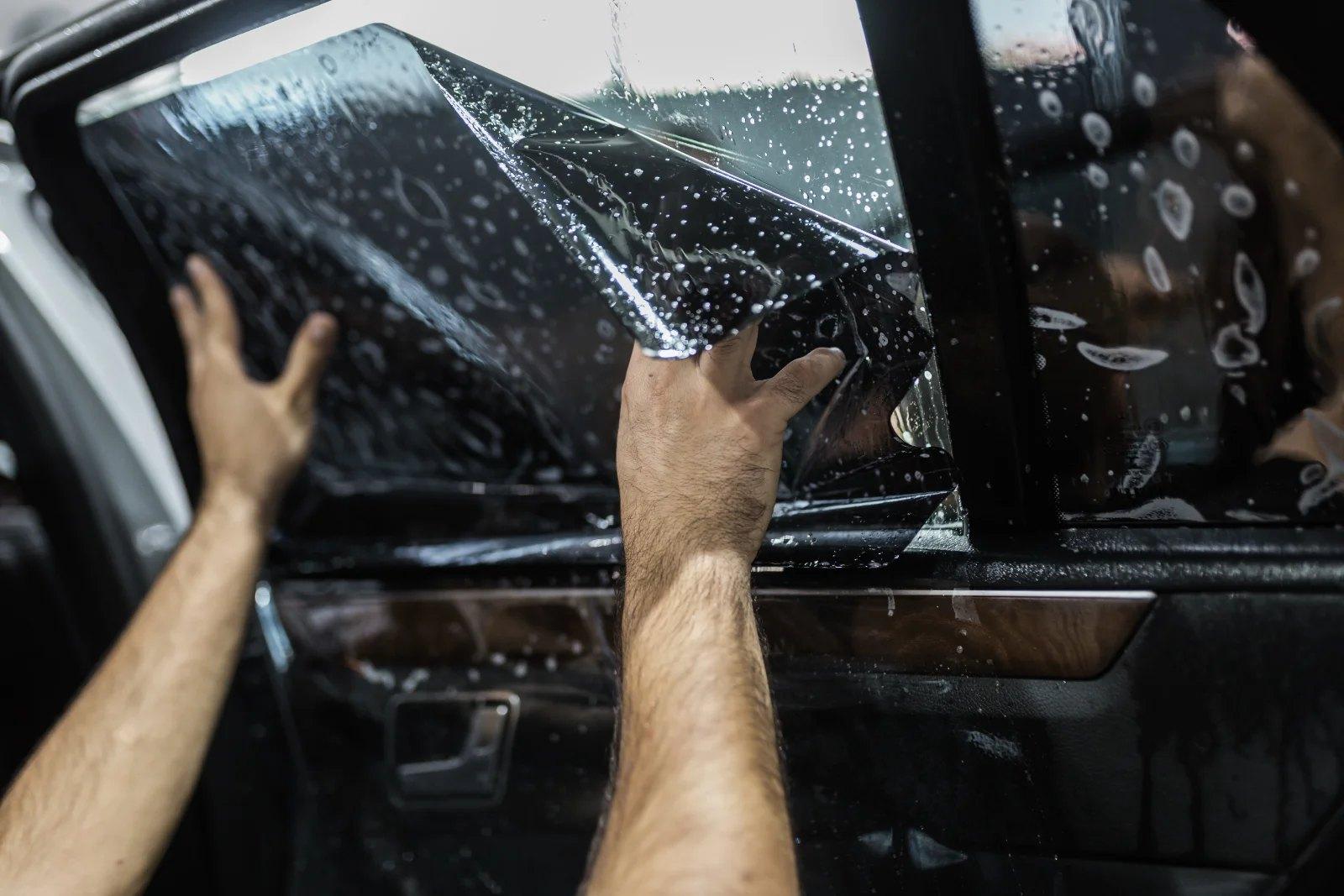 Installer smoothing wet automotive window tint film onto a car door window