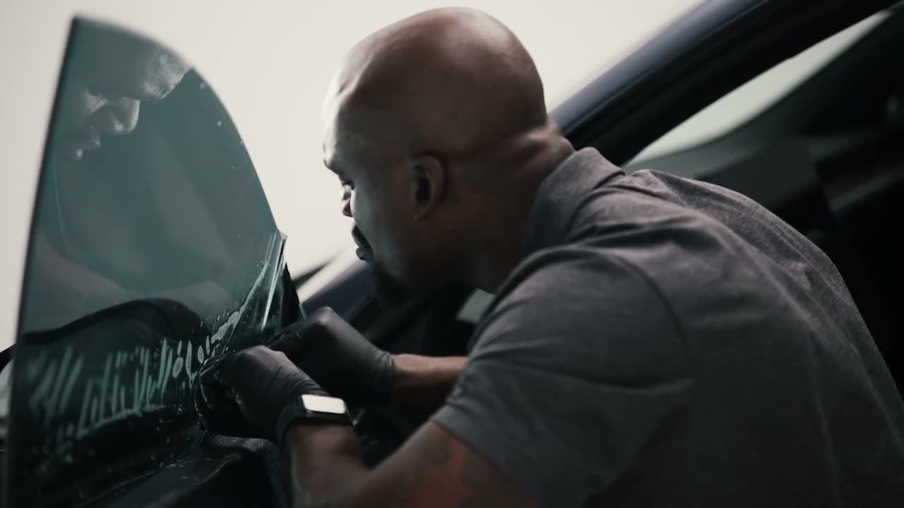 Installer fitting window film on a car door